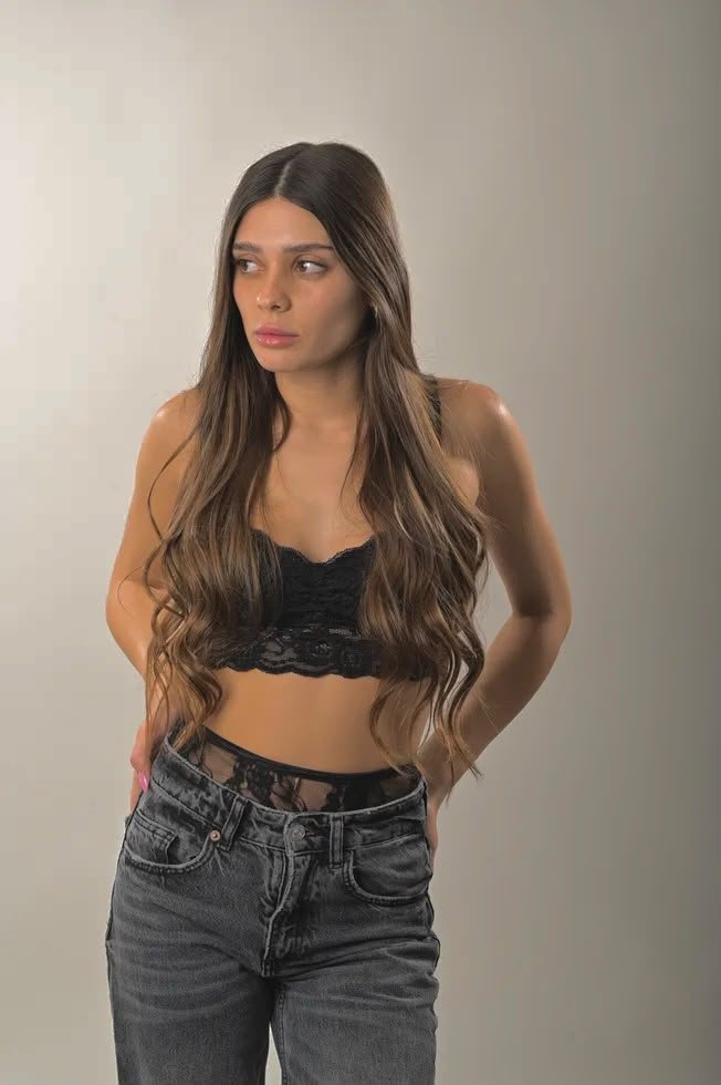 פורטרט סטודיו של אישה בטופ תחרה שחור וג׳ינס, רקע בהיר