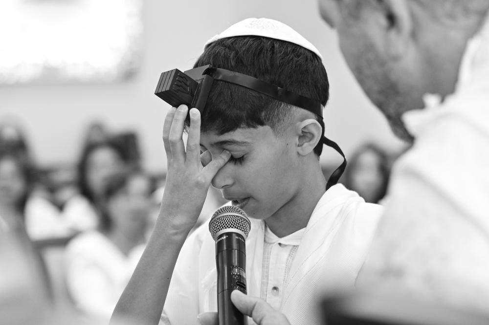 תמונת שחור־לבן של נער עם תפילין ליד מיקרופון