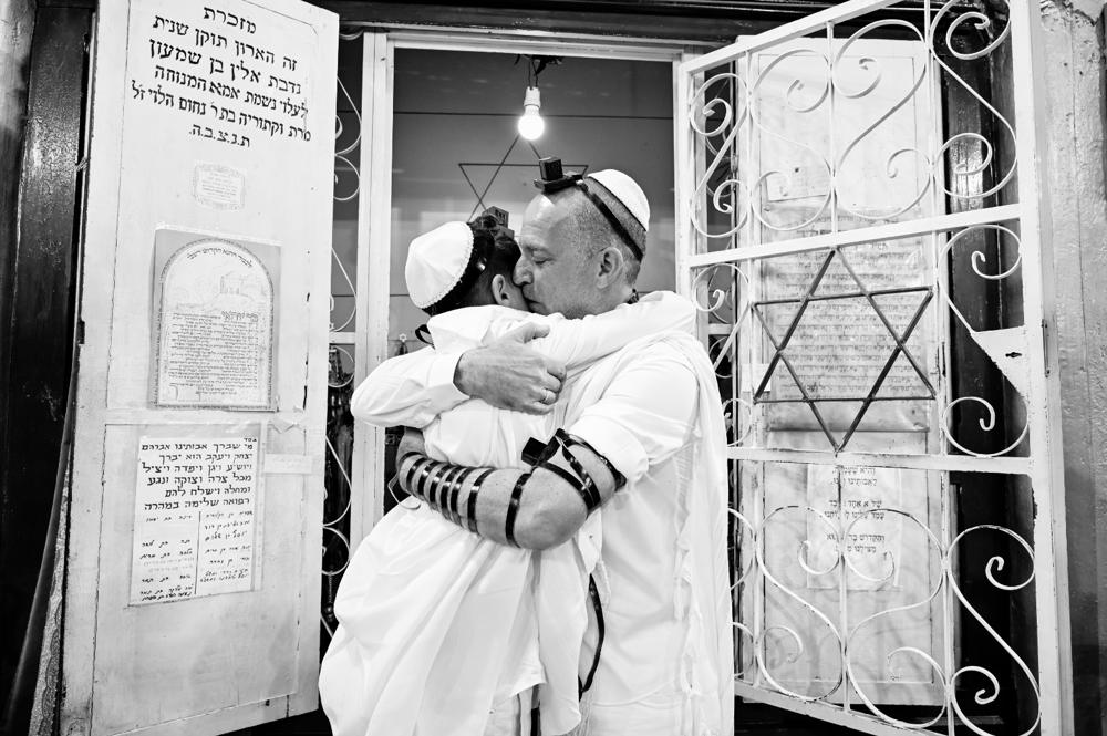 תמונת שחור־לבן של אב מחבק את בנו בעת תפילה