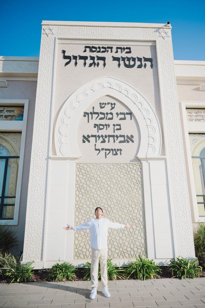 נער בזרועות פרושות מול חזית בית כנסת